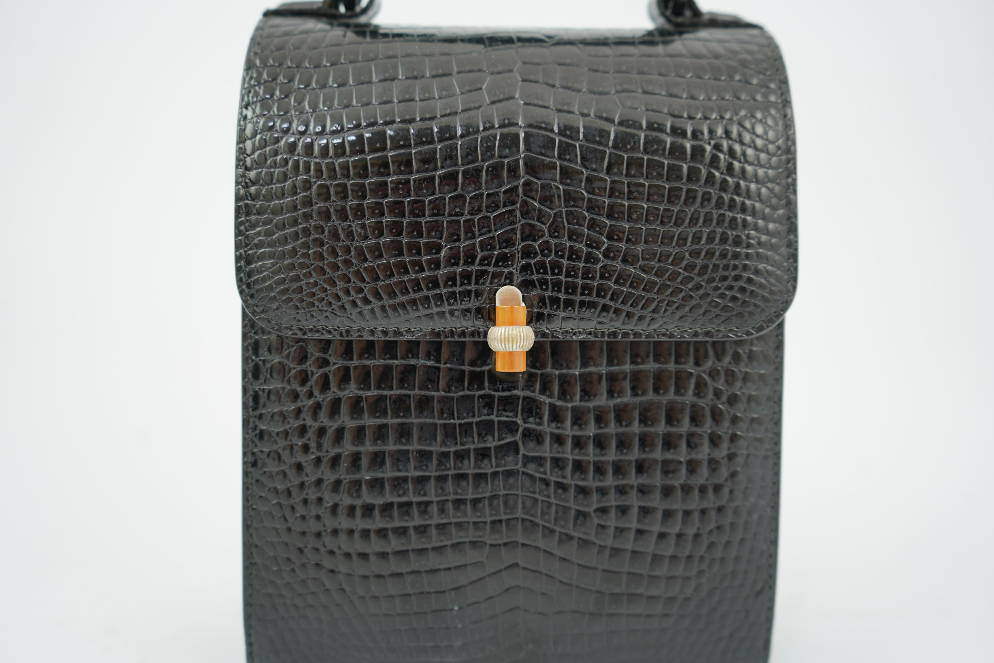 A stylish 1930’s lady’s Asprey of London, black lizard skin evening bag with ornamental amber coloured Bakelite clasp. 23cm high from handle to base. Condition- some internal scratches to lining as expected for age and u